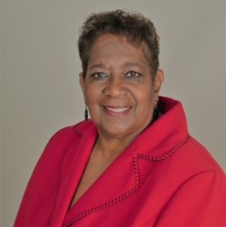 zoomed in, color image of Linda Tillman. She is wearing a red shirt and against a beige colored background