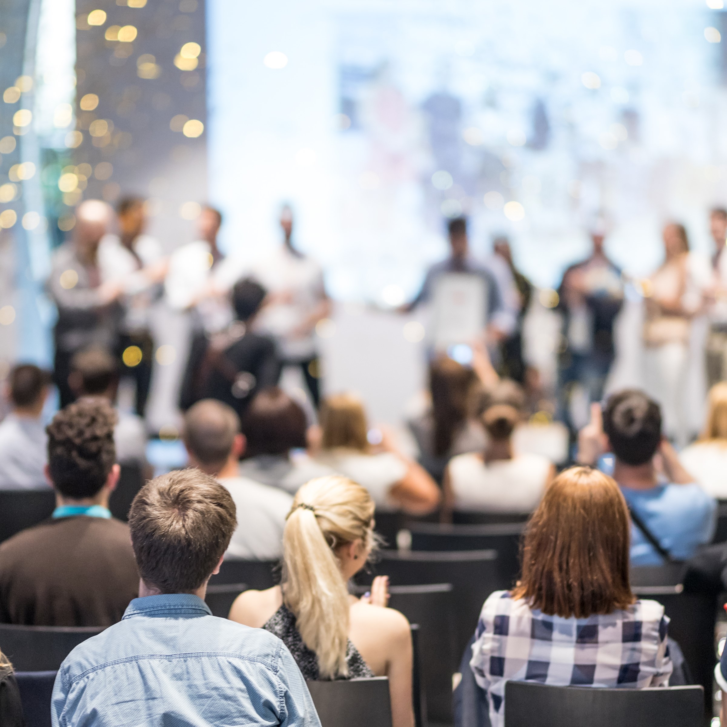 Stock image of audience looking at people on a stage